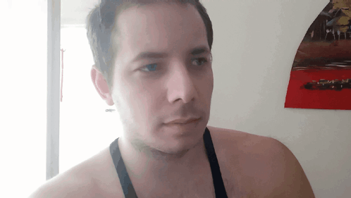 A Man Without A Shirt Is Standing In Front Of A Wall With A Picture Of Cars On It GIF
