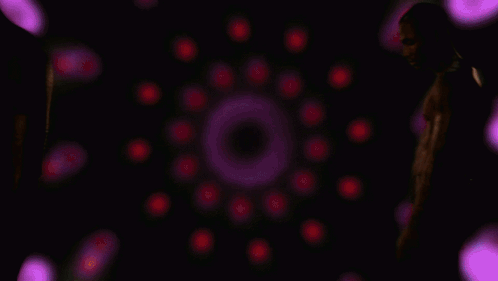 A Man Without A Shirt Is Standing In Front Of Purple Lights GIF