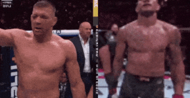 A Man Without A Shirt Is Standing Next To Another Shirtless Man In A Boxing Ring GIF