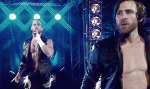 A Man Without A Shirt Is Standing Next To Another Shirtless Man On A Stage GIF