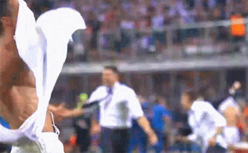 a man without a shirt is standing on a soccer field with a white shirt on