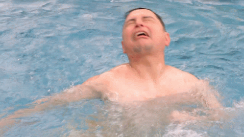 A Man Without A Shirt Is Swimming In A Pool With His Mouth Open GIF