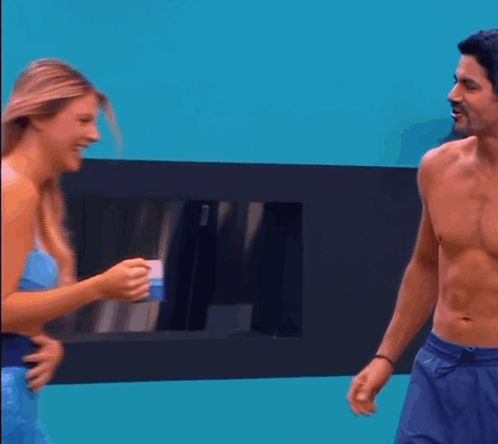 A Man Without A Shirt Is Talking To A Woman In A Mermaid Costume GIF
