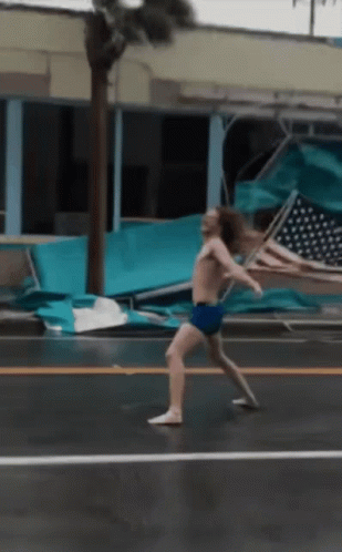 A Man Without A Shirt Is Walking Down A Street GIF