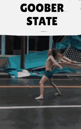 a man without a shirt is walking down a street with a sign that says goober state
