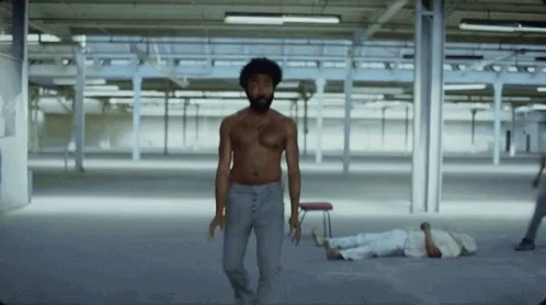 A Man Without A Shirt Is Walking In An Empty Room While A Man Laying On The Floor . GIF