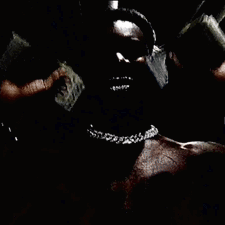 A Man Without A Shirt Is Wearing A Chain Around His Neck In A Dark Room . GIF