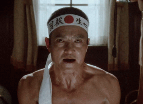 A Man Without A Shirt Is Wearing A Headband With Chinese Characters On It GIF