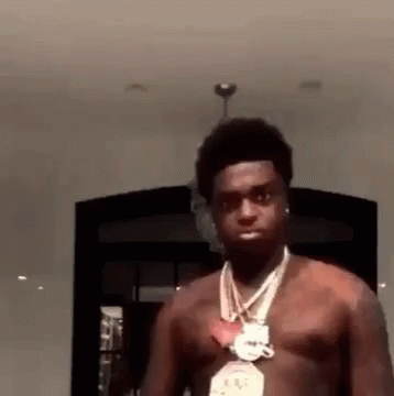 A Man Without A Shirt Is Wearing A Necklace And Earrings . GIF