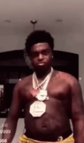 A Man Without A Shirt Is Wearing A Necklace Around His Neck . GIF