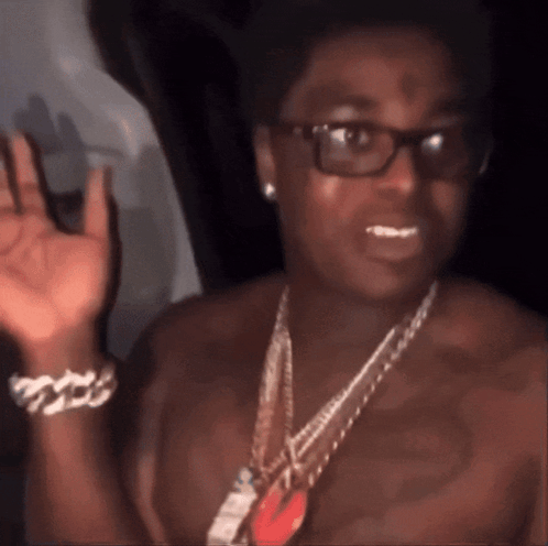 A Man Without A Shirt Is Wearing Glasses And A Chain GIF