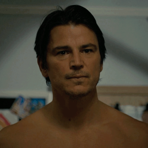 A Man Without A Shirt Looks At The Camera With A Serious Look On His Face GIF