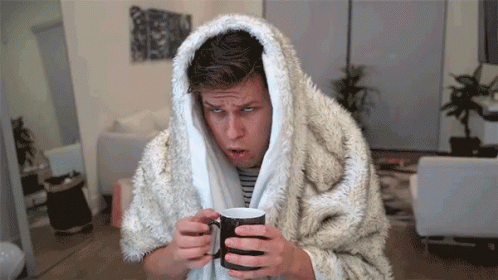 A Man Wrapped In A Furry Blanket Holds A Cup Of Coffee GIF
