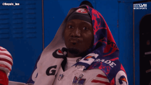 A Man Wrapped In A Gatorade Blanket Looks At Something GIF