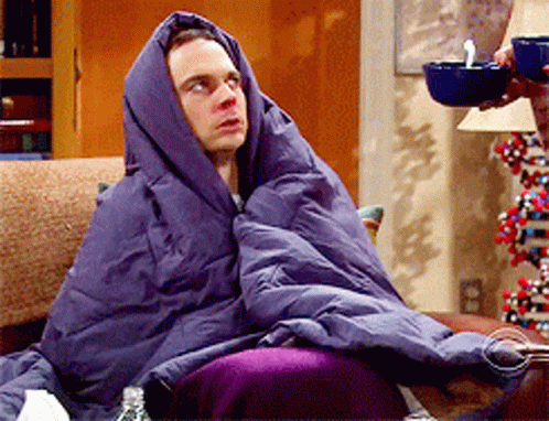A Man Wrapped In A Purple Blanket Sits On A Couch GIF