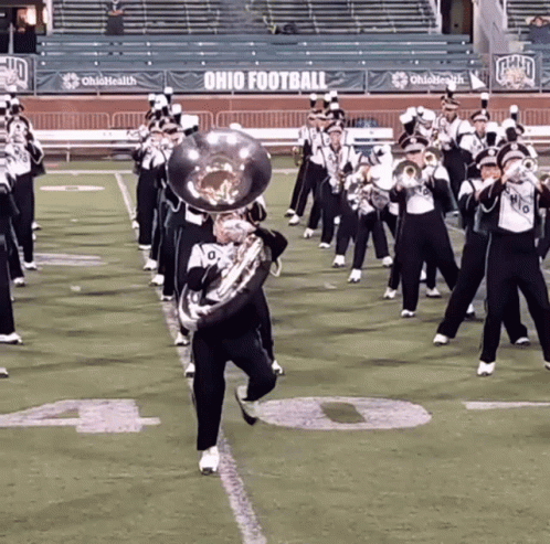 a marching band performs on a field with ohio football banners