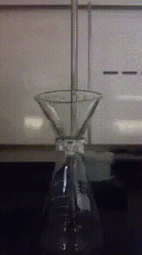A Martini Glass Is Sitting On A Table In Front Of A White Cabinet GIF