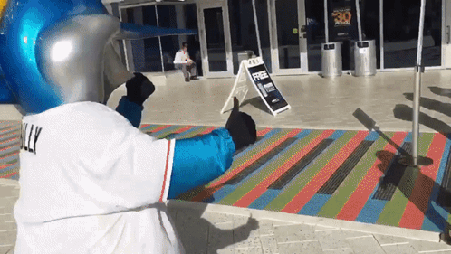 A Mascot Giving A Thumbs Up In Front Of A Sign That Says Free Parking GIF