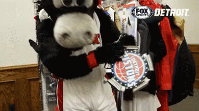 A Mascot In A Detroit Pistons Uniform Holds A Trophy GIF