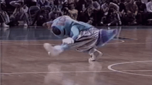 A Mascot Is Doing A Trick On A Basketball Court While A Crowd Watches . GIF