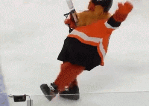 A Mascot Is Holding A Hockey Stick And Falling On The Ice . GIF