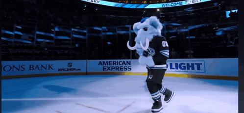 A Mascot Is On The Ice In Front Of An American Express Banner GIF