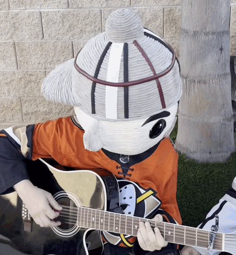 A Mascot Is Playing A Guitar And Wearing A Hockey Jersey GIF