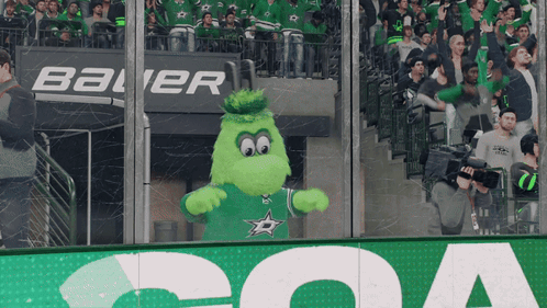A Mascot Is Standing In Front Of A Bauer Sign GIF