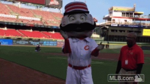 A Mascot On A Baseball Field With A Mlb.com Logo In The Background GIF