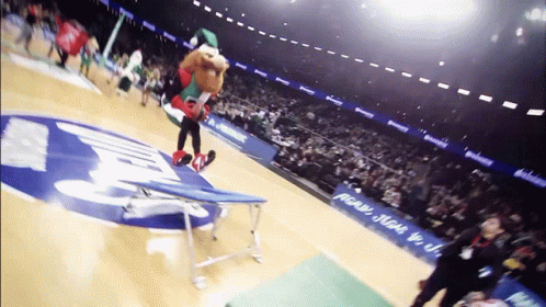 A Mascot Performs A Trick On A Trampoline In Front Of A Sign That Says ' Pecan ' On It GIF