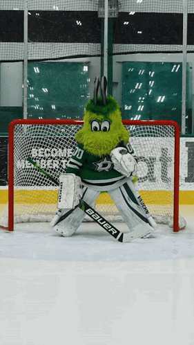 A Mascot Wearing A Bauer Goalie 'S Glove Is Standing In Front Of A Net GIF