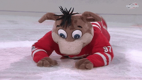 A Mascot Wearing A Red And White Jersey With The Number 97 On It Is Laying On The Ice . GIF