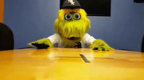 A Mascot Wearing A White Sox Hat Sits At A Conference Table GIF