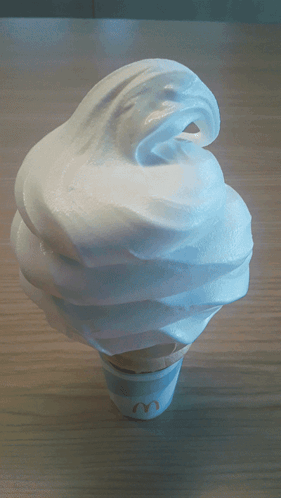 A Mcdonald 'S Soft Serve Ice Cream Cone With Whipped Cream On Top GIF