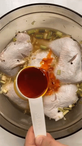 A Measuring Spoon Is Being Used To Pour Sauce Into A Bowl Of Chicken GIF