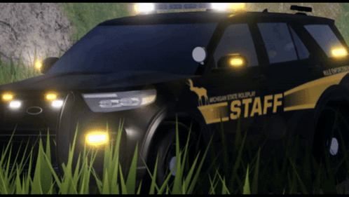 A Michigan State Police Car Is Parked In A Grassy Field GIF