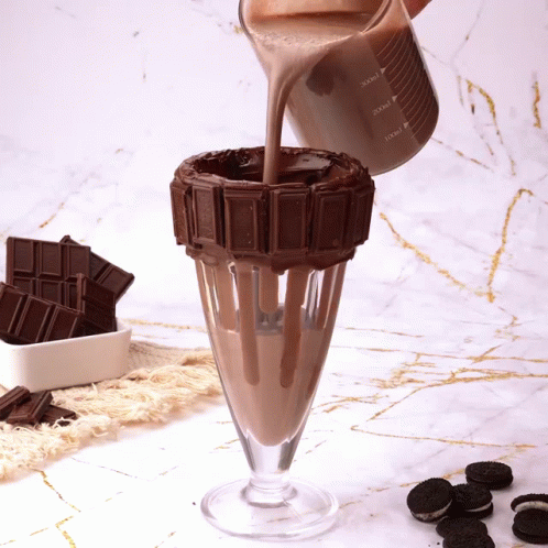A Milkshake Is Being Poured Into A Glass With A Chocolate Decoration GIF