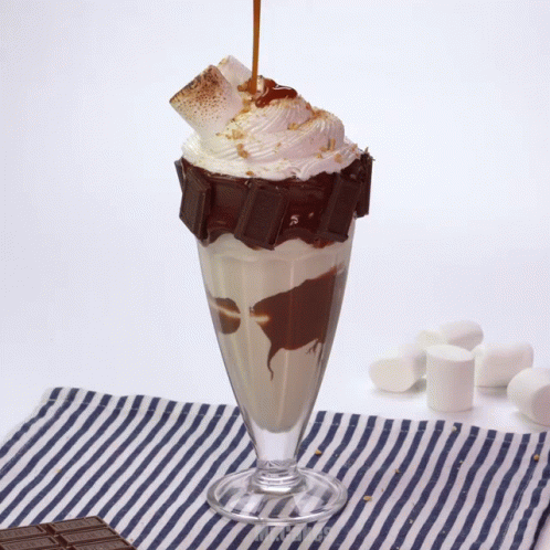 A Milkshake With A Chocolate Bar On Top And Whipped Cream GIF