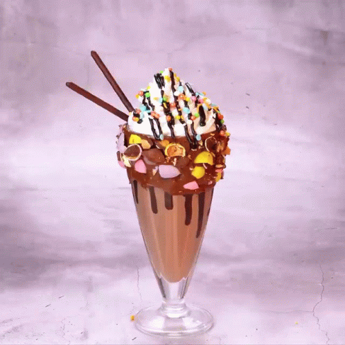 A Milkshake With M & M 'S And Oreos On Top Of It GIF