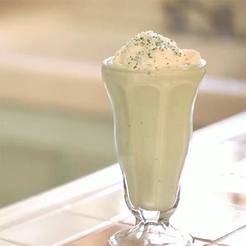 A Milkshake With Whipped Cream And Green Sprinkles On Top GIF