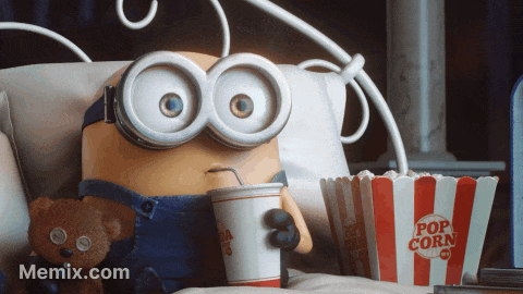 A Minion Is Sitting On A Bed With A Cup Of Soda And A Bucket Of Popcorn GIF