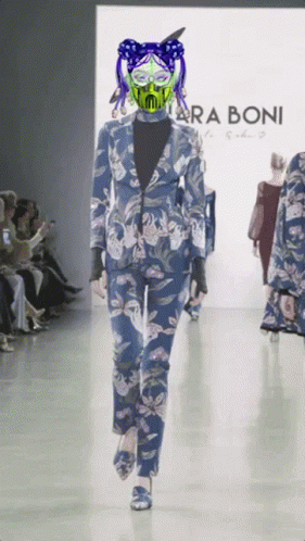 A Model Walks Down A Runway Wearing A Blue Suit And A Green Mask By Taraboni GIF