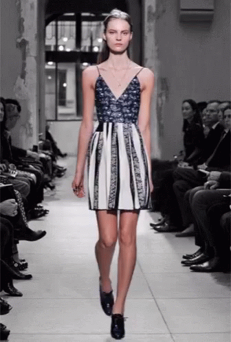 A Model Walks Down The Runway At A Fashion Show Wearing A Blue And White Dress GIF