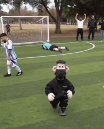 A Monkey Mascot Is Running On A Soccer Field In Front Of A Goalie GIF
