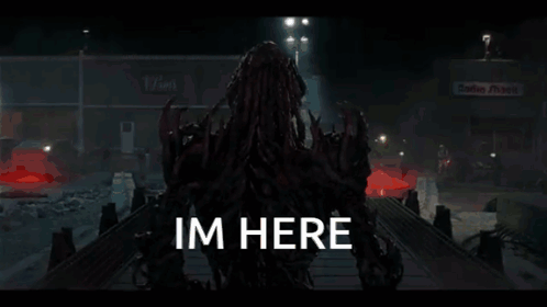 A Monster Is Standing In A Dark Room With The Words Im Here Written On The Bottom . GIF