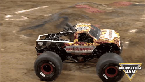 A Monster Jam Truck Is Driving On A Dirt Road GIF