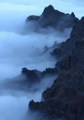 A Mountain Covered In Clouds With The Word Greeting Visible In The Corner GIF