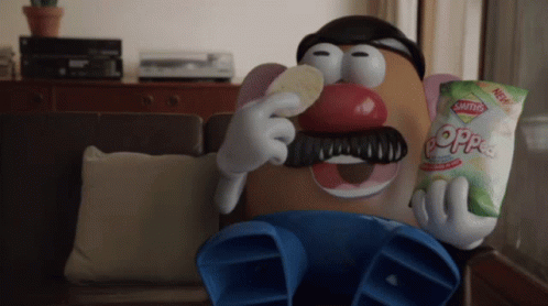 A Mr Potato Head Is Sitting On A Couch Eating A Bag Of Saltines GIF