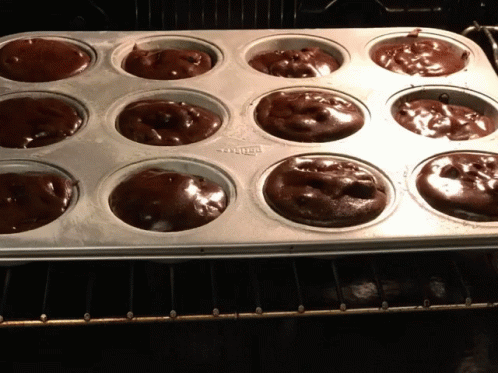 A Muffin Pan Filled With Chocolate Cupcakes Is Sitting On A Rack GIF