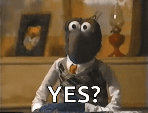 a muppet is sitting at a table with the words yes written on it